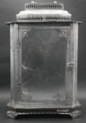 A contemporary silver metal pierced design glass storm lantern with carrying handle. H.50cm