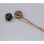 Two antique gemset stick pins. One oval yellow metal pin set to centre with a cushion shape Ceylon