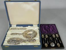 A sterling silver cased repousse brush set decorated with faces, birds and scrolling foliate design,