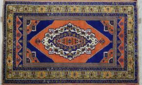 An Eastern rug with central floral lozenge medallion on blue ground within stylised spandrels and