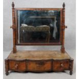 A Georgian mahogany toilet mirror of serpentine outline fitted with frieze drawers on turned squat