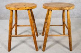 A pair of early 20th century elm seated stools on beech supports. H.53cm