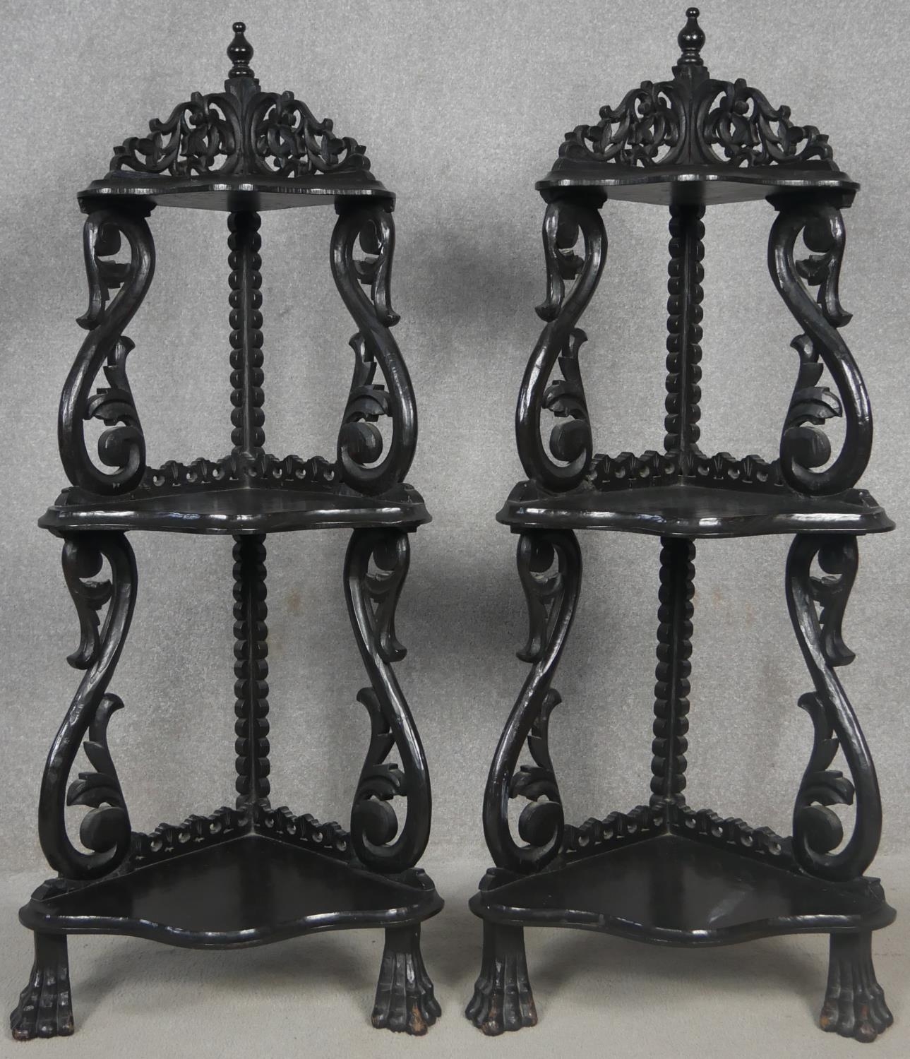 A pair of Burmese hardwood corner whatnots, carved and pierced, raised on paw feet. H.123cm