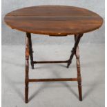 A 19th century walnut folding table on turned stretchered supports. H.65 D.76cm