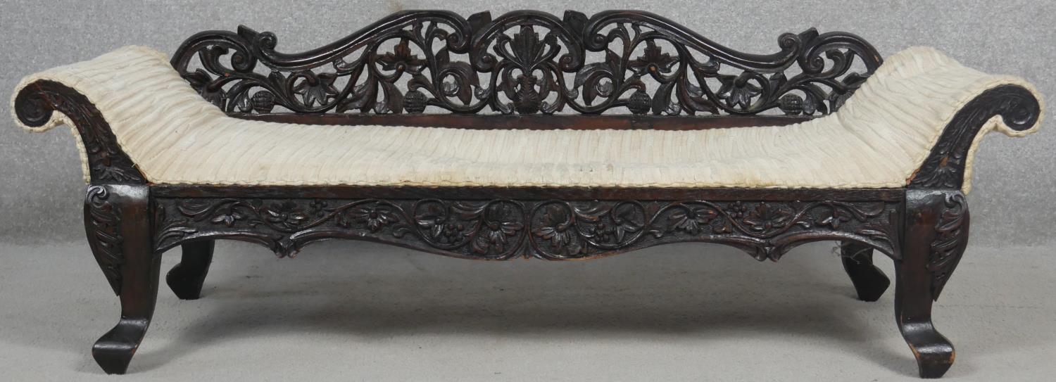 A miniature Burmese hardwood double end chaise longue with all over carved and pierced decoration.