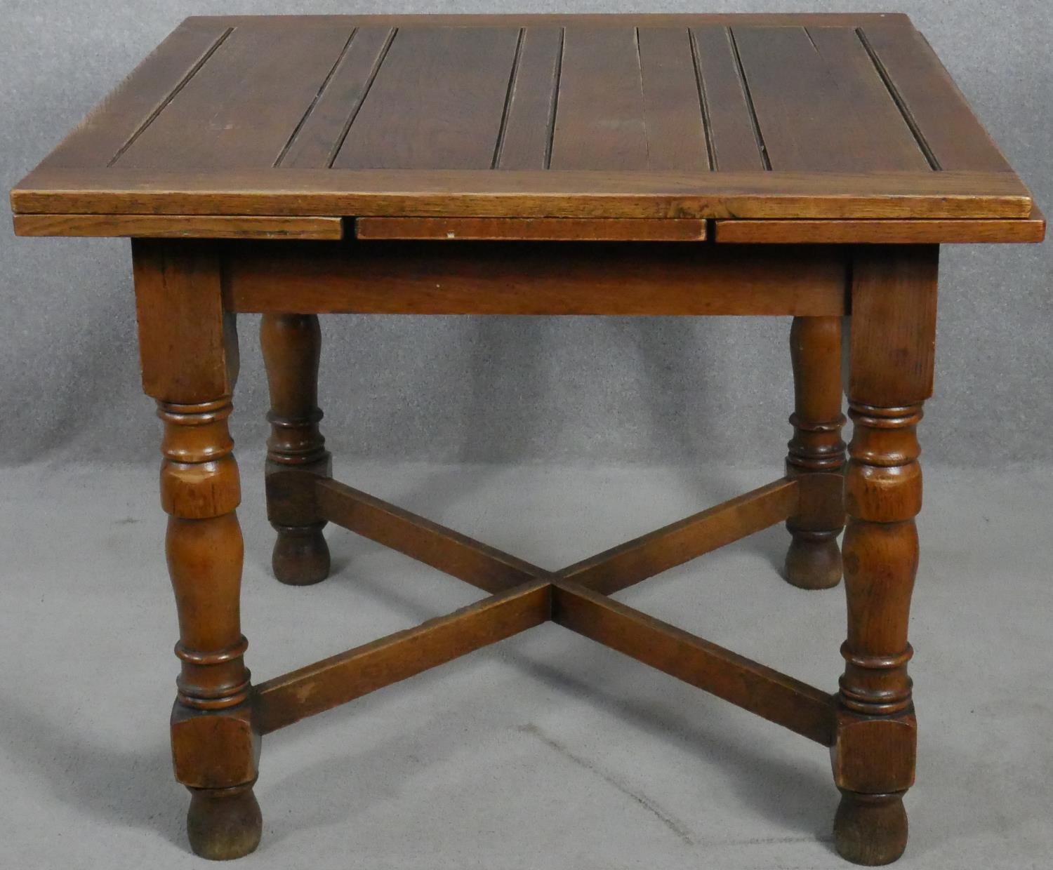 A mid century oak draw leaf table on turned stretchered supports. H.75 W.92 D.92cm