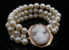 A yellow metal (tested 9ct) shell cameo and three strand cultured pearl bracelet. The push clasp,