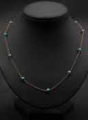 A 9 carat yellow gold and turquoise bead chain necklace, set with eleven round turquoise beads,