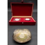 A white metal repousse Indian dish set to centre with a 1918 1 rupee coin, decorated with