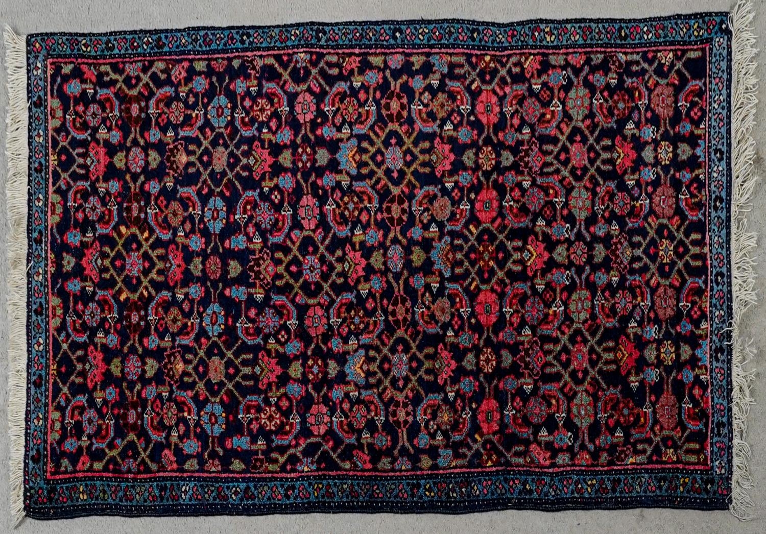 A Eastern rug with stylised floral motifs across the midnight ground within foliate borders. L.140