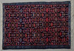 A Eastern rug with stylised floral motifs across the midnight ground within foliate borders. L.140