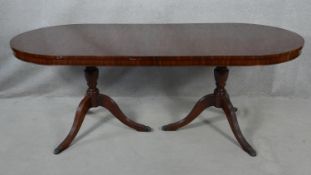 A Georgian style mahogany twin pillar dining table with extra leaf on reeded tripod swept