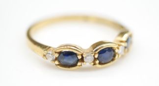 A three stone sapphire, diamond and 18 carat yellow gold ring. Set with three oval mixed cut