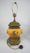 A brass table lamp base of facetted baluster form with heraldic motif and twin handles. H.72 W.27