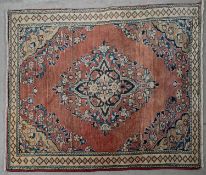 A Persian style rug with central floral medallion on a madder ground within naturalistic floral