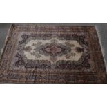 A Persian style carpet with central floral medallion on fawn ground contained by naturalistic floral