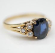 A sapphire and diamond 14 carat yellow gold flanked solitaire ring. Set to centre with an oval mixed