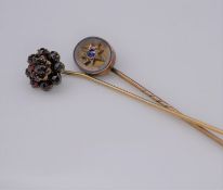 Two antique gemset stick pins. One oval yellow metal pin set to centre with a cushion shape Ceylon