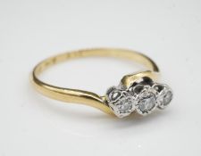 An 18 carat yellow gold, platinum and diamond three stone cross over ring. Set to centre with a