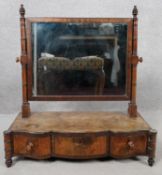 A Georgian mahogany toilet mirror of serpentine outline fitted with frieze drawers on turned squat