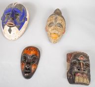 A collection of four carved and painted polychrome tribal masks. H.58 W.45cm