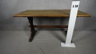 A vintage oak country antique style dining table on stretchered trestle supports and maker's label