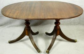 A Georgian style mahogany dining table with extra leaf on twin pedestal reeded swept supports