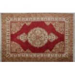 A Persian style rug with central floral medallion on burgundy ground within naturalistic floral