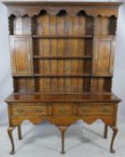 A Georgian style oak dresser with open plate rack fitted with cupboards above three drawers with