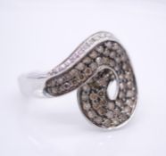 An 18 carat white gold diamond and champagne diamond spiral design dress ring. Set with twenty round