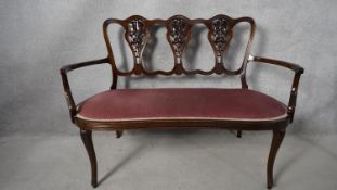 A late 19th century mahogany salon sofa with carved and pierced triple chair back on slender