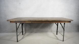 A refectory style dining table with planked and cleated top on folding metal base. H.78 W.192 D.66