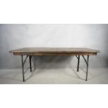 A refectory style dining table with planked and cleated top on folding metal base. H.78 W.192 D.66