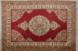 A Persian style rug with central floral medallion on burgundy ground within naturalistic floral