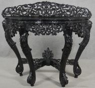 A Burmese hardwood console table with all over carved and pierced decoration on stretchered cabriole