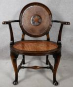 An early 20th century mahogany framed office armchair with caned back and seat on stretchered