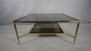A vintage brass framed two tiered coffee table with smokey plate glass top and undertier. H.47 W.101