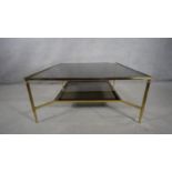 A vintage brass framed two tiered coffee table with smokey plate glass top and undertier. H.47 W.101