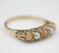 A Victorian style carved 9 carat coral and pearl ring five stone ring. Set with two half pearls