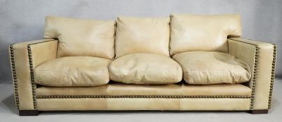 An Andrew Martin three seater sofa in studded leather upholstery resting on block supports. H.90 W.