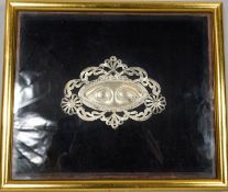 A framed and glazed silver Venetian Milagro mask made from pierced white metal with scrolling and