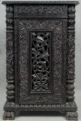 A Burmese hardwood cabinet with all over carved decoration and pierced panel door resting on paw