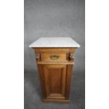 A late 19th century oak pedestal cabinet with marble top above frieze drawer and panel door