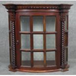 A Continental style mahogany wall hanging cabinet with glazed panel door flanked by spiral