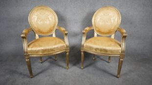 A pair of carved giltwood Louis XVI style armchairs in floral damask upholstery raised on tapering