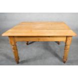 A 19th century pine kitchen table with frieze drawer fitted for cutlery raised on turned tapering