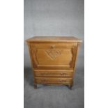 A Continental light oak drinks cabinet with carved fall above two drawers on cabriole supports. H.