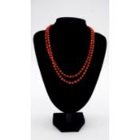 A 14 carat gold and coral long chain necklace comprised of 134 polished barrel shaped coral beads