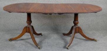 A Georgian style mahogany and crossbanded D-end dining table raised on carved twin pedestal swept