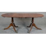 A Georgian style mahogany and crossbanded D-end dining table raised on carved twin pedestal swept